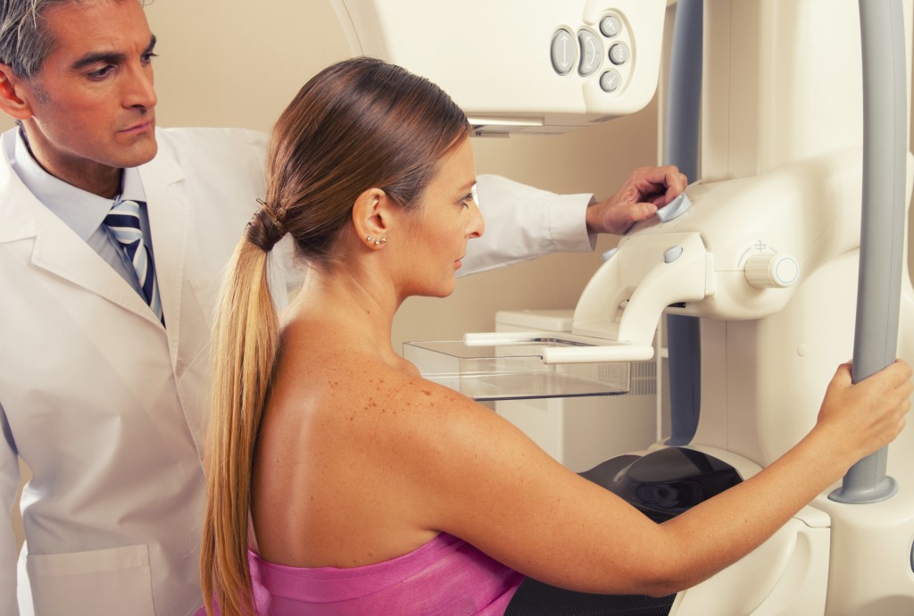 Male doctor checking mammography machine scan with patient woman